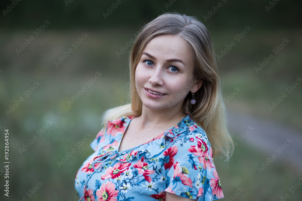 Portrait of young beautiful smiling woman in flower vintage dress on the background of green grass. Portrait of young beautiful smiling woman in flower vintage dress on the background of green grass.
