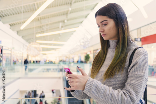 A young girl reading a message on a mobile phone in a shopping center