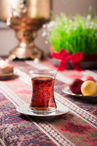 Novruz setting table decoration, tea in tulip shape glass on ethnic motives rustic table cloth with wheat grass, dyed eggs, traditional sweets, samovar, new year sring celebration, nature awakening
