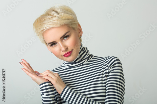 beautiful young girl with short hairdo on a light background with seductive facial expressions on her face