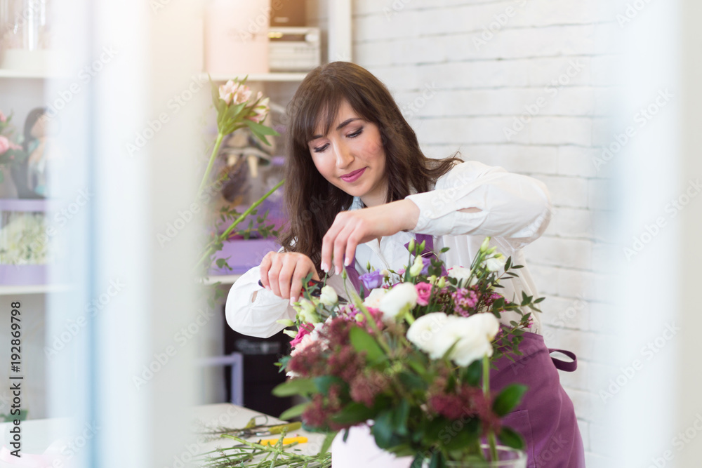 Young happy florist making fresh flowers arrangement in gift box for a holidays Young happy florist making fresh flowers arrangement in gift box for a holidays