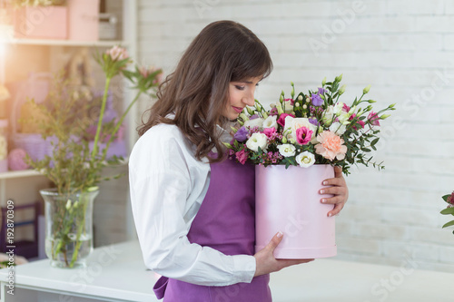 Young happy florist making fresh flowers arrangement in gift box for a holidays
