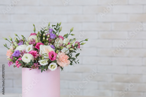 Bouquet of different flowers for holidays on white table with brick wall background, copy space