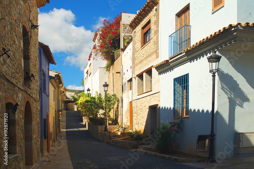 Small european village street under the sun with flowers