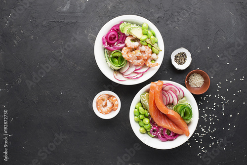 Fresh seafood recipe. Shrimp salmon poke bowl with fresh prawn, brown rice, cucumber, pickled sweet onion, radish, soy beans edamame portioned with black and white sesame. Food concept poke bowl. Top