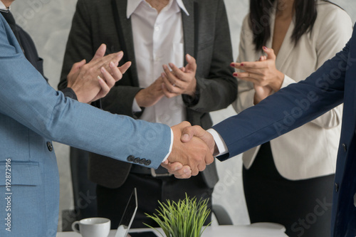 Two business man checking hand to success deal after meeting while another people applauding. Close-up