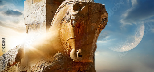 Fragment of the statue of a horse in ancient Persepolis against the background of the sun and the moon. Sights of Iran. Day and night together. Alien planet concept. photo