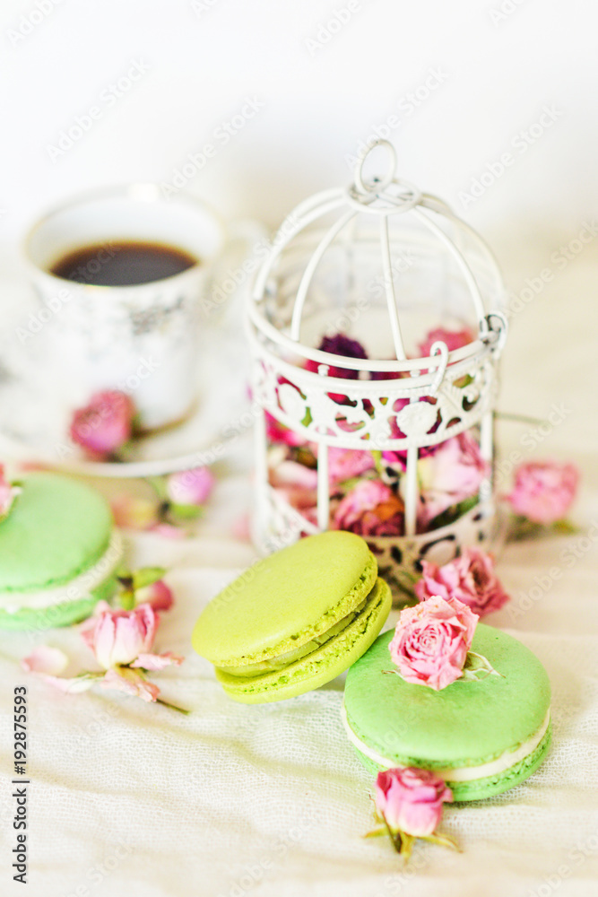 Dessert: A Delicate Fresh Colorful French Macaroons In Pastel Colors With Flowers Roses On A Light Textile Background, Top View Dessert: A Delicate Fresh Colorful French Macaroons In Pastel Colors With Flowers Roses On A Light Textile Background, Top View