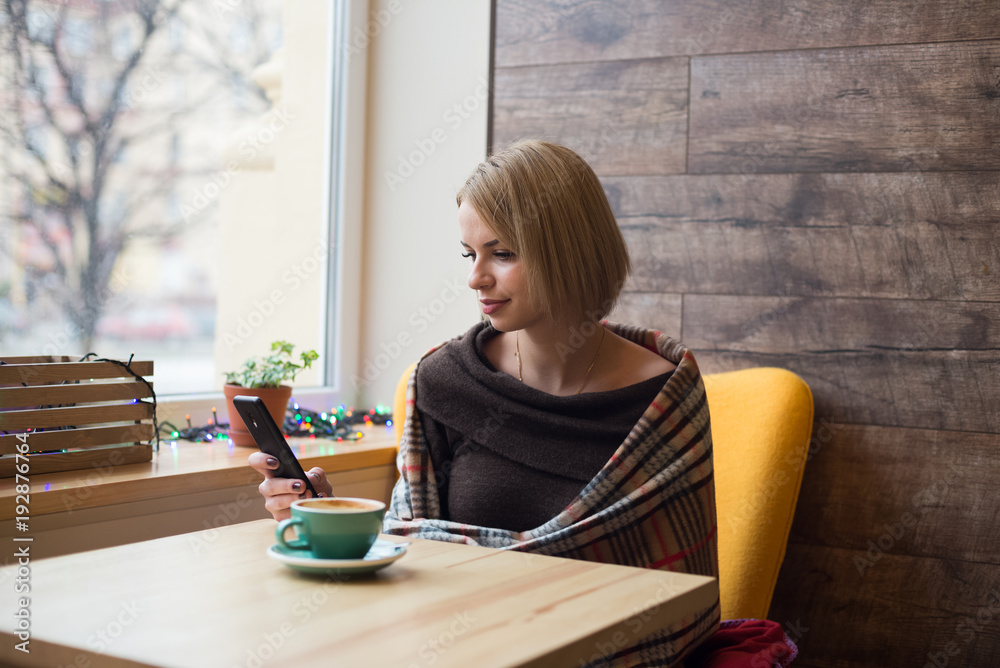 Woman drinking coffee in the morning at cafe. Soft focus on the eyes. Sellphone on table. Woman drinking coffee in the morning at cafe. Soft focus on the eyes. Sellphone on table.