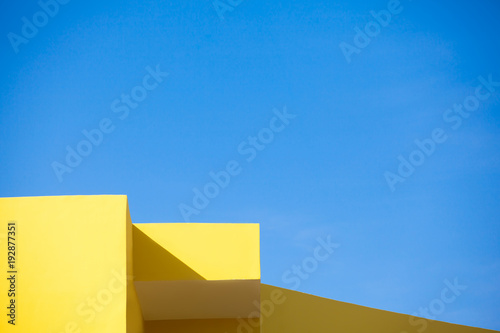 Corners of a yellow building against blue sky. Geometric background. 