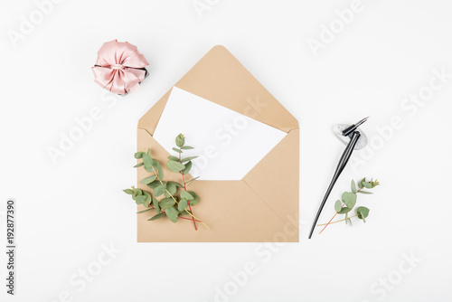 Beige craft envelope, gift box with pink ribbon and eucalyptus franches. Top view and flat lay with copy space. photo