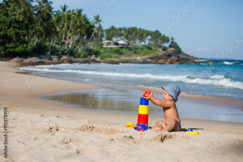 Fototapeta Naklejka Na Ścianę i Meble -  Kid plays with toys at the seashore in summertime