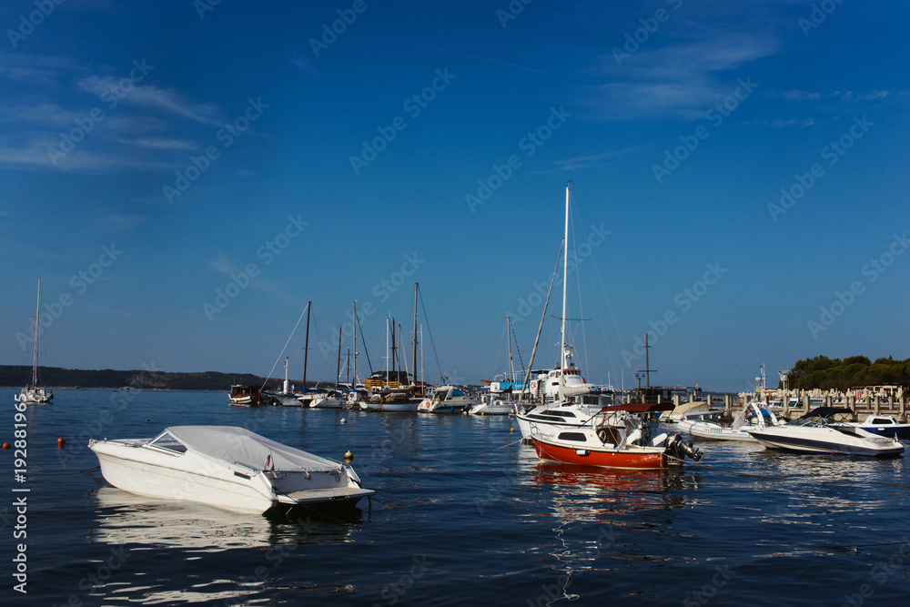 Yachts parking pier in Portoroz Slovenia. Bright blue water of Mediterranean sea on clear summer sky