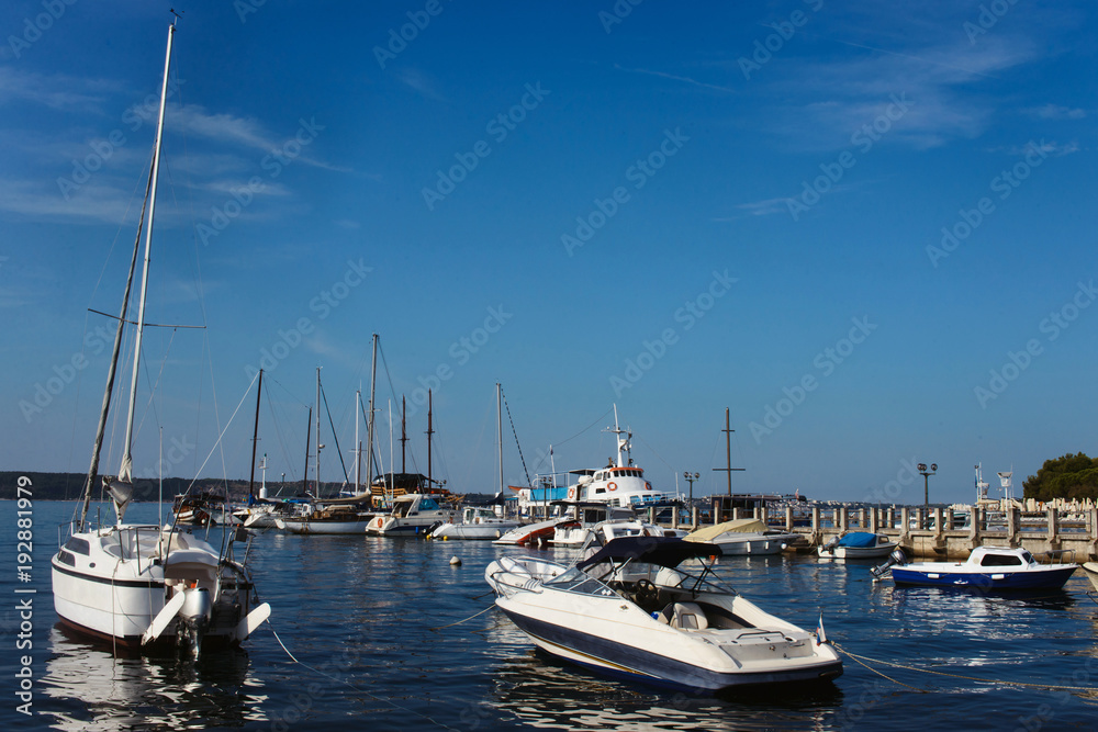 Yachts parking pier in Portoroz Slovenia. Bright blue water of Mediterranean sea on clear summer sky