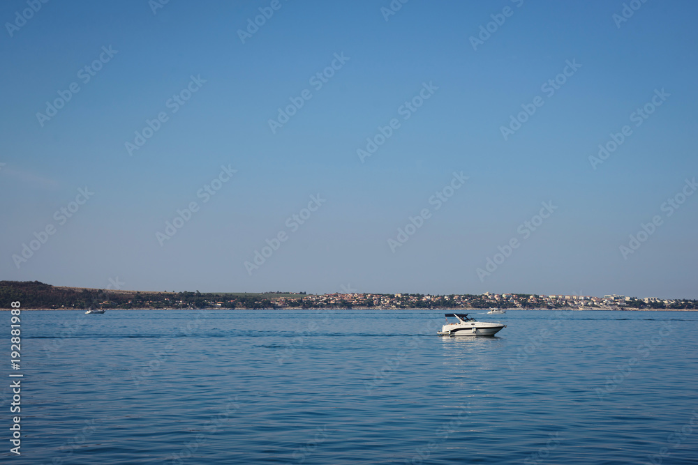Motorboat sailing on the sea, quiet cruise on the blue water, active rest summer vacation. Pier city background