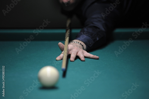 Billiard: a pool player gets ready to stroke a ball with a cue photo