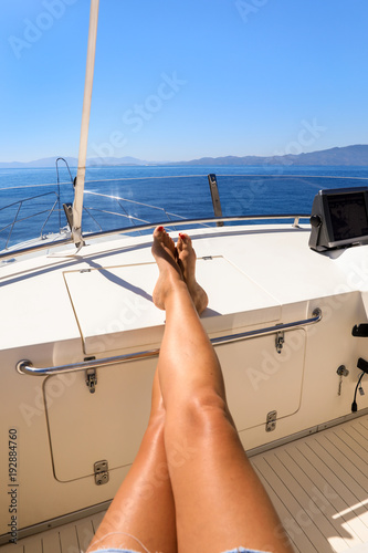 Long legs of a young woman on a yacht in the open sea having a rest start to travel with pleasure relax summer holidays concept.