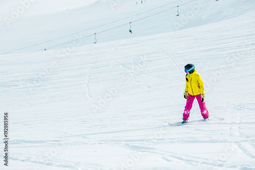 Image of young athletic girl wearing helmet in sports clothes snowboarding