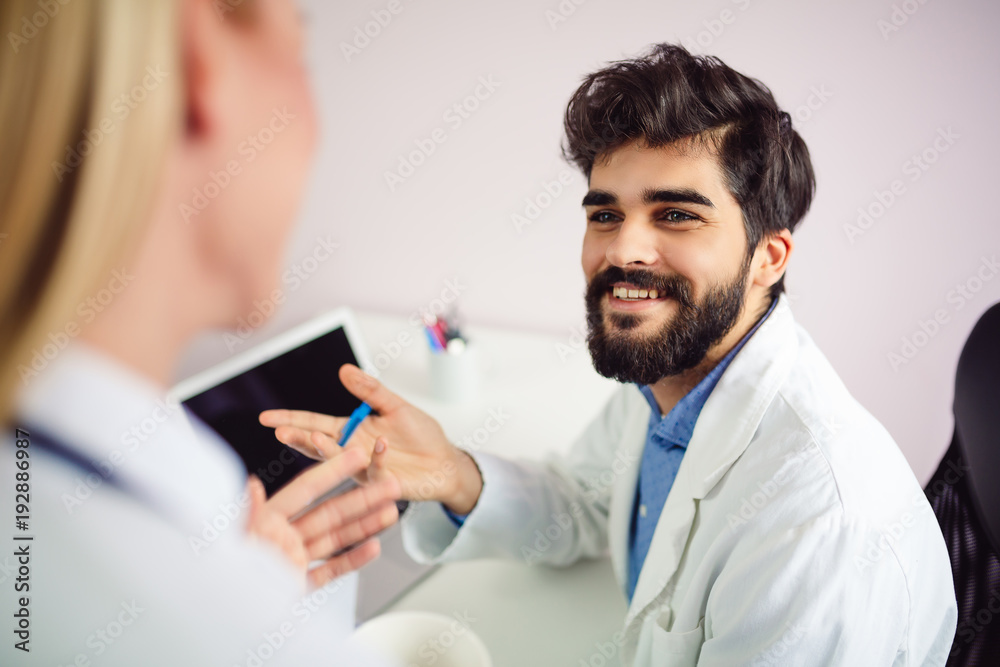 Portrait of young smiling male doctor talking with his colleague. Portrait of young smiling male doctor talking with his colleague.