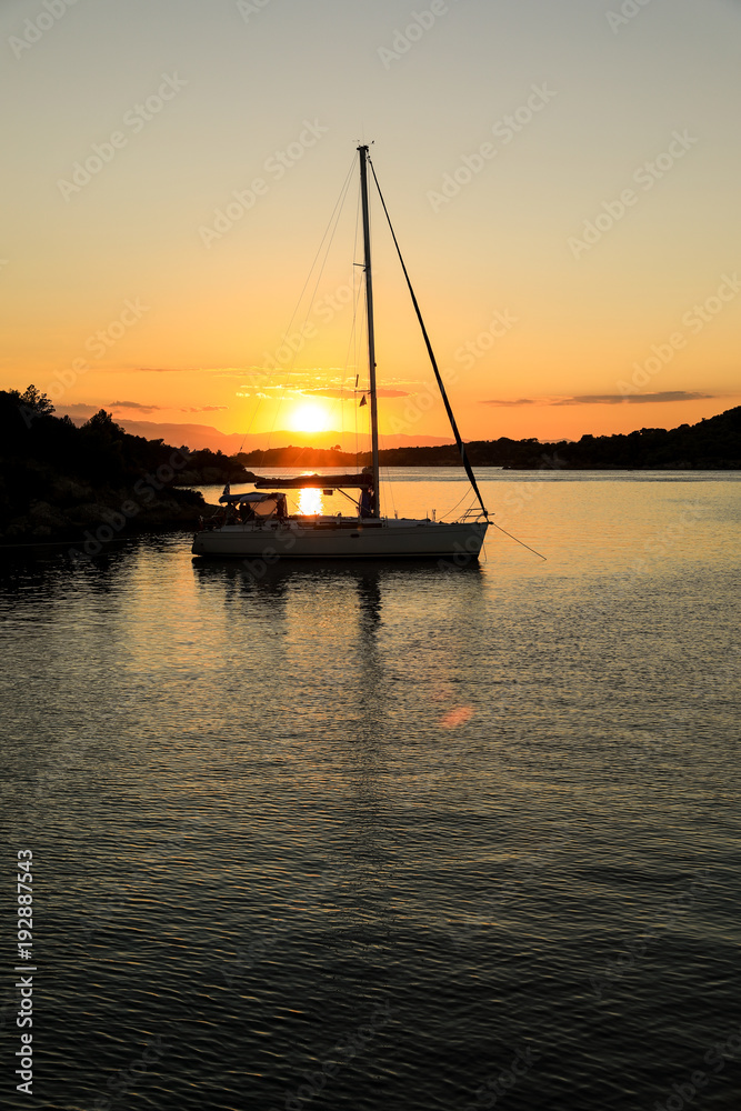 Beautiful sunset sailboat anchoring in a bay near Porto Heli, Peloponnese, Greece.