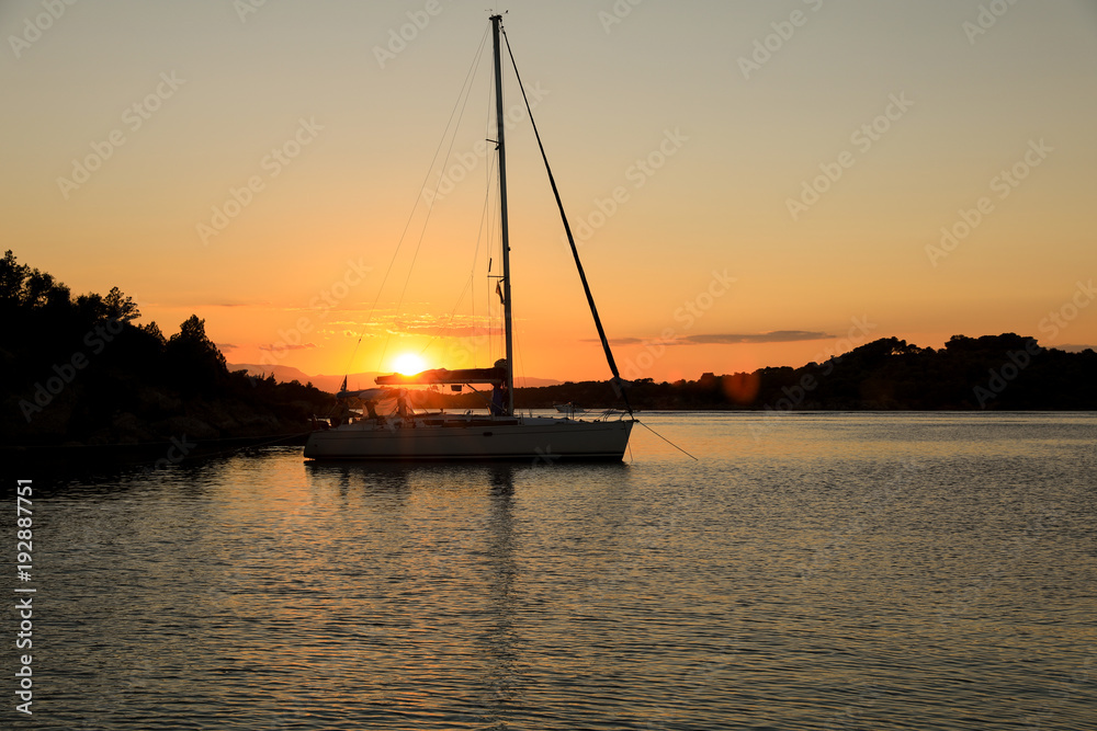 Beautiful sunset sailboat anchoring in a bay near Porto Heli, Peloponnese, Greece.