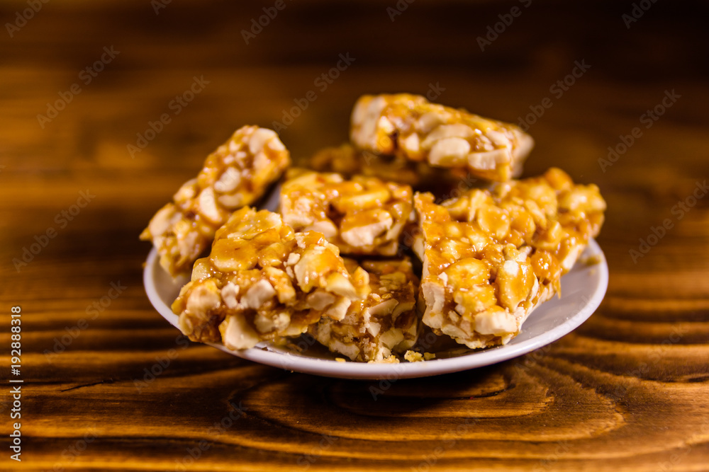 Ceramic plate with peanut brittles on wooden table. Ceramic plate with peanut brittles on wooden table.