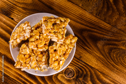 Ceramic plate with peanut brittles on wooden table. Top view