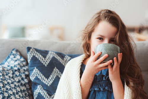 child girl drinking hot tea to recover from flu. Healing kids and protect immunity from seasonal virus, health concept photo