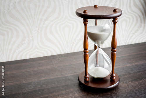 Hourglass or Sandglass on a wooden desk showing time left. A countdown to an event. With copy space.