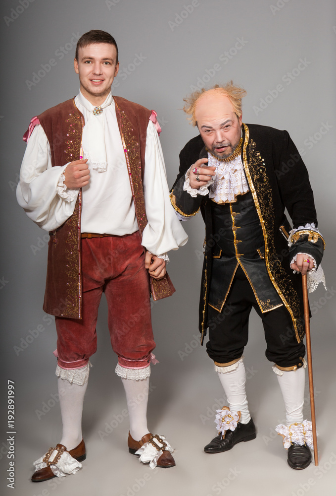 The title characters of France of the 17th century. An old nobleman with a  young man servant on a gray background in the studio. Actors in costumes.  Stock Photo | Adobe Stock