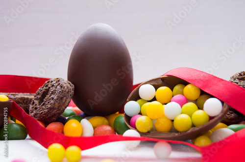 Chocolate easter egg with candy and red ribbon