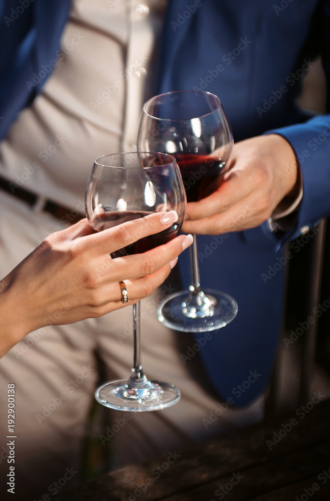 Close up portrait of a female and male couple hands toasting with glasses of red wine