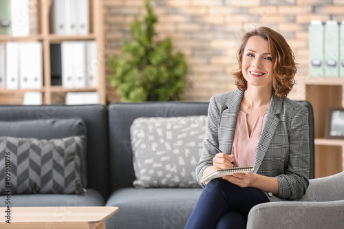 Attractive female psychologist sitting in armchair at office photo