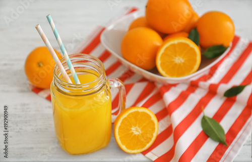 Mason jar with fresh orange juice and fruit on wooden table