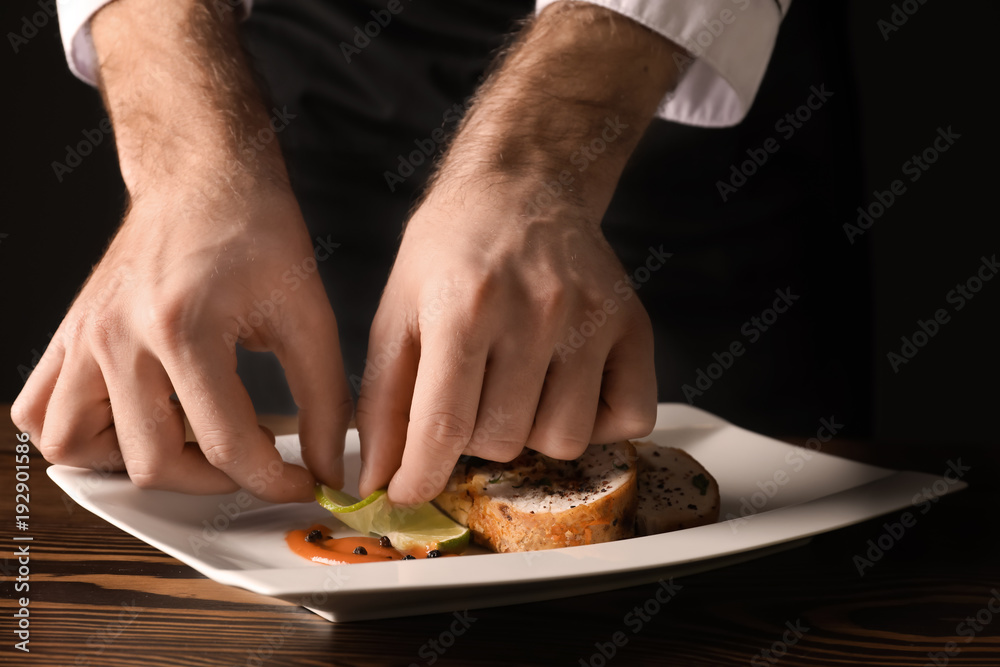 Male chef in uniform preparing tasty dish on table, closeup