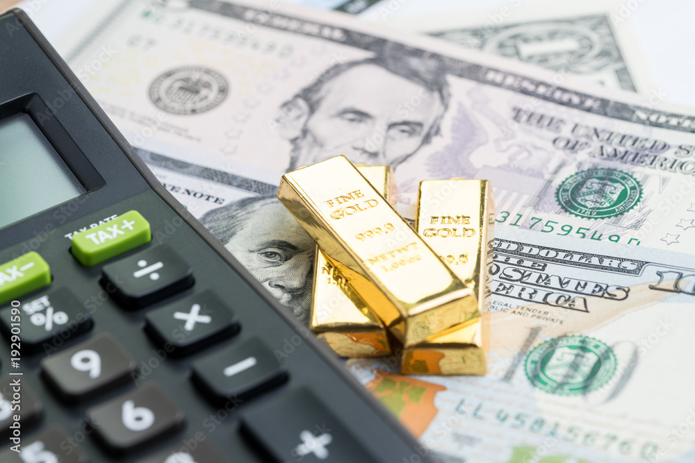 Fototapeta premium Success investment or financial wealth calculation concept, gold bars / ingot on pile of money US dollar banknotes with calculator
