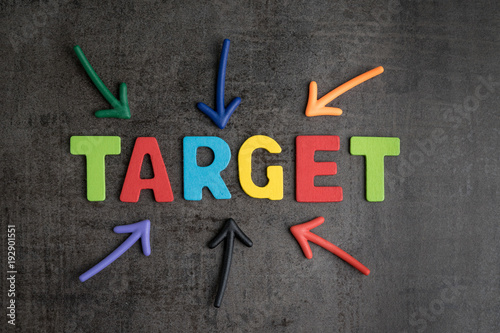 Business aiming target plan for success concept, multi colorful magnet arrows pointing at wooden letters the word TARGET at the center on chalkboard loft cement wall