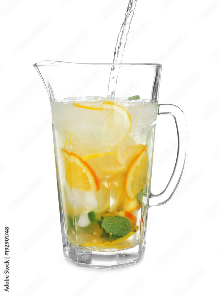 Pouring fresh lemonade into jug on white background Pouring fresh lemonade into jug on white background