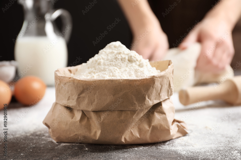 Paper bag with flour and woman making dough on background Paper bag with flour and woman making dough on background