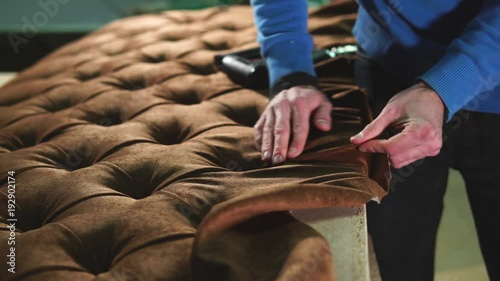 Wallpaper Mural Cabinet maker is wrapping a sofa with a cloth. He is tightening fabric and fixing it with industrial stapling machine in a workshop of factory Torontodigital.ca
