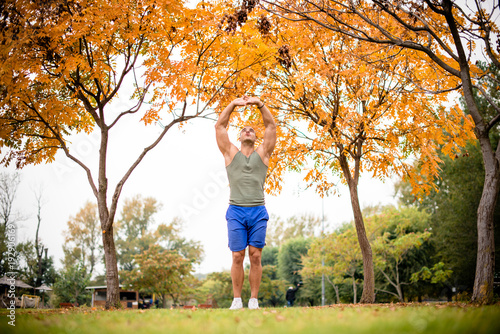 Fit man stretching arms in park