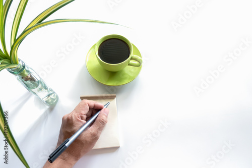 White office desk table with blank notebook, cup of coffee.Top view with copy space.