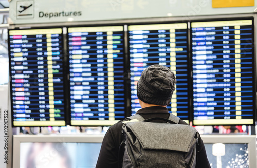 a man with backpack looking on departure flight information board, for travel, go back home and holiday trip