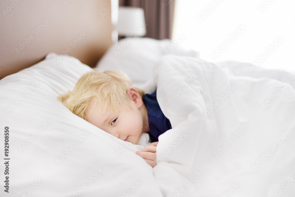 Cute little boy sleeping. Tired child taking a nap in parent's bed.