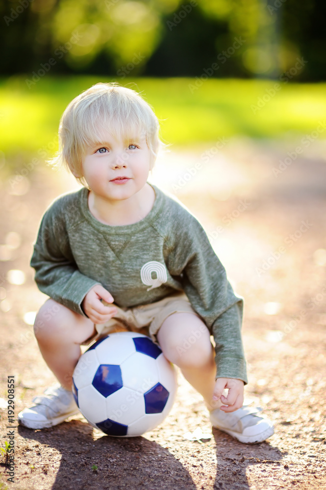 Little boy having fun playing a soccer/football game on summer day Little boy having fun playing a soccer/football game on summer day