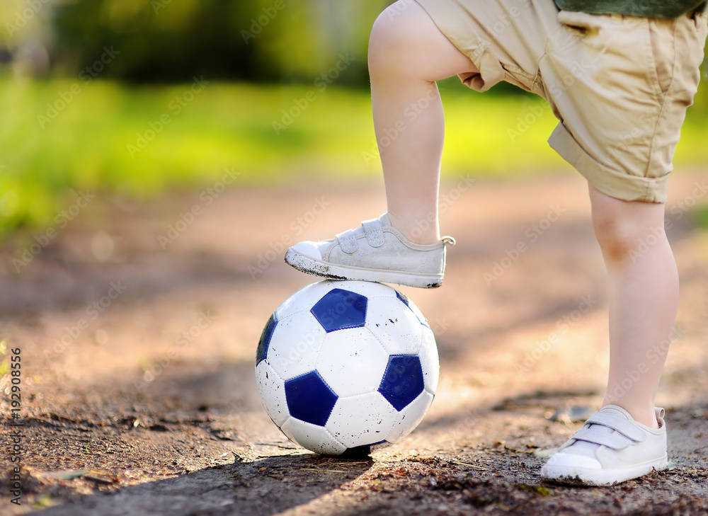 Little boy having fun playing a soccer/football game on summer day Little boy having fun playing a soccer/football game on summer day