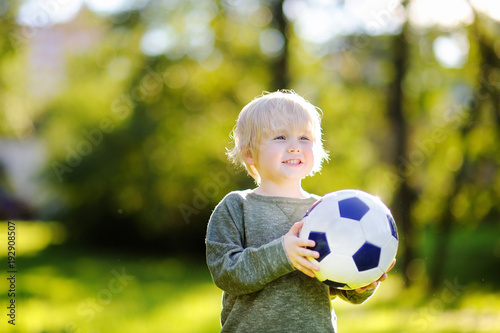 Little boy having fun playing a soccer game on sunny summer day
