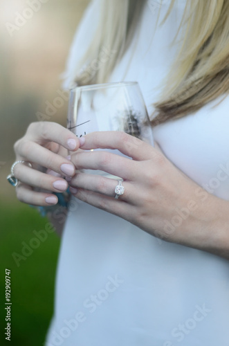 Girl with diamond ring hold wine glass at sunset