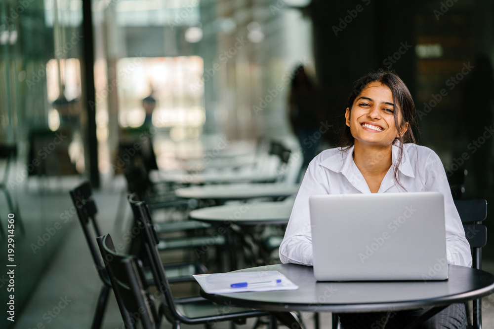 A young job-seeker applies for her job on her laptop computer. It is a portrait of a young and attractive Indian lady sitting at a table as she smiles and fills in her application. A young job-seeker applies for her job on her laptop computer. It is a portrait of a young and attractive Indian lady sitting at a table as she smiles and fills in her application.