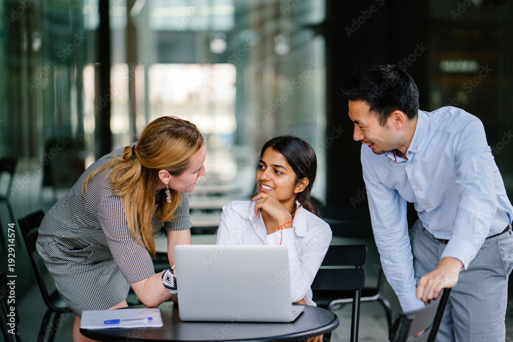 An image of meeting in the office between a variety of professionals. As they discuss a topic in a group, they look at a laptop for reference and smile. An image of meeting in the office between a variety of professionals. As they discuss a topic in a group, they look at a laptop for reference and smile.